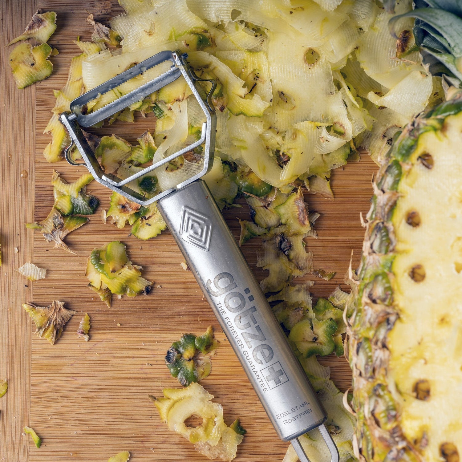 Pineapple peeler on a wooden cutting board with sliced pineapple pieces