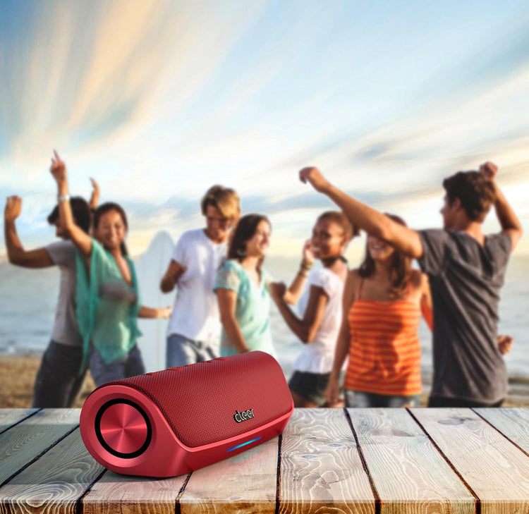 Red portable speaker on a wooden surface with people dancing in the background