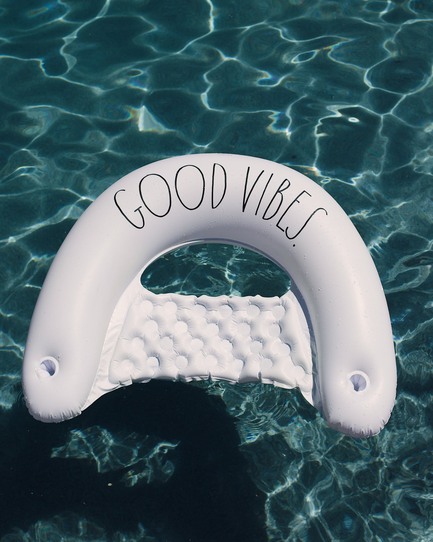 Inflatable pool toy with 'Good Vibes' text floating on water
