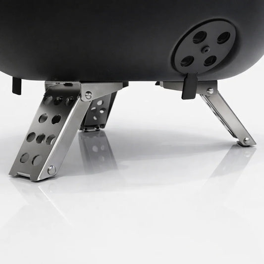 Portable grill with food being cooked on a wooden table outdoors