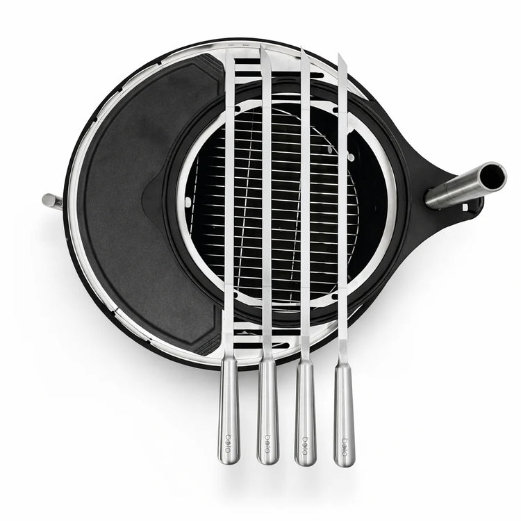 Black and silver grill with four metal skewers on a white background