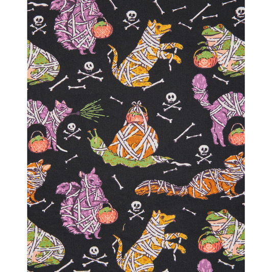 Woman wearing a black pajama top with colorful cat pattern outdoors.