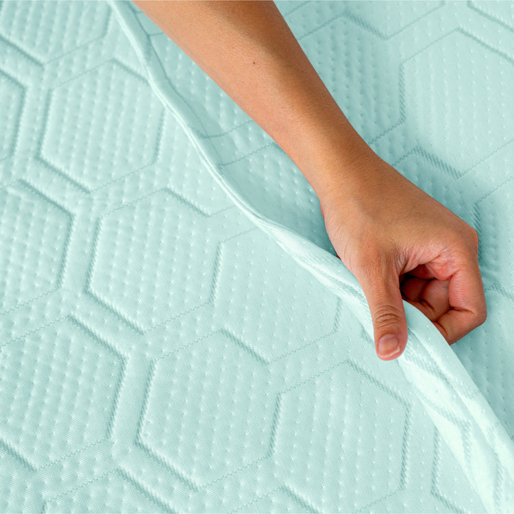 Hand touching a textured light blue mattress pad
