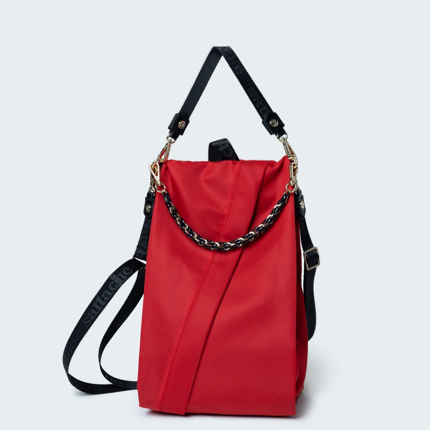 Red bag with black straps and chain detail on a light gray background