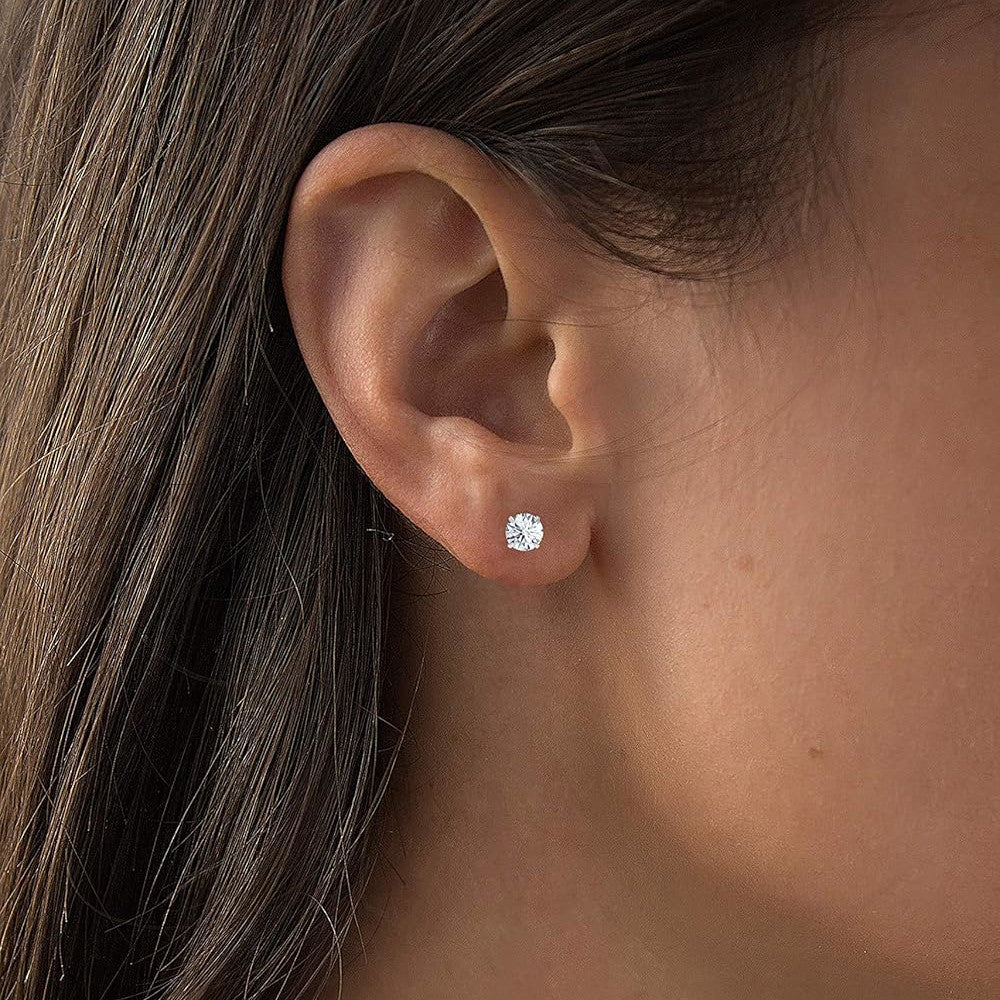 Close-up of an ear wearing a diamond stud earring with hair partially obscuring the view.
