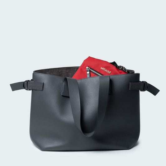 Red bag with black straps and chain detail on a light gray background
