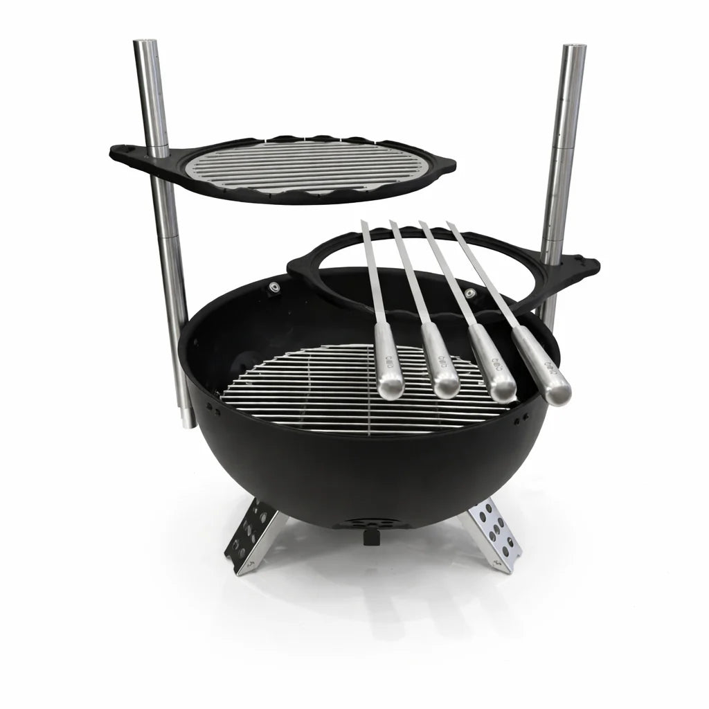 Black portable grill with additional cooking surface and skewers on a white background