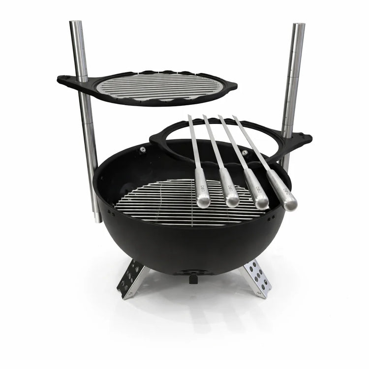 Black portable grill with additional cooking surface and skewers on a white background