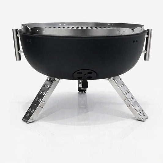 Portable grill with food being cooked on a wooden table outdoors
