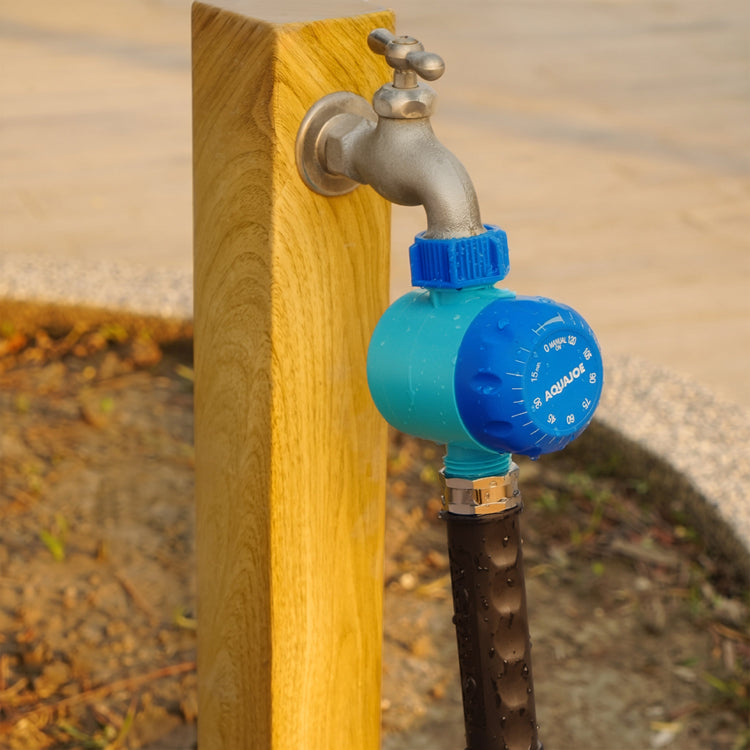 A close-up outdoor shot of a blue and turquoise smart water flow controller attached to a metal faucet mounted on a wooden post, with a black hose below.