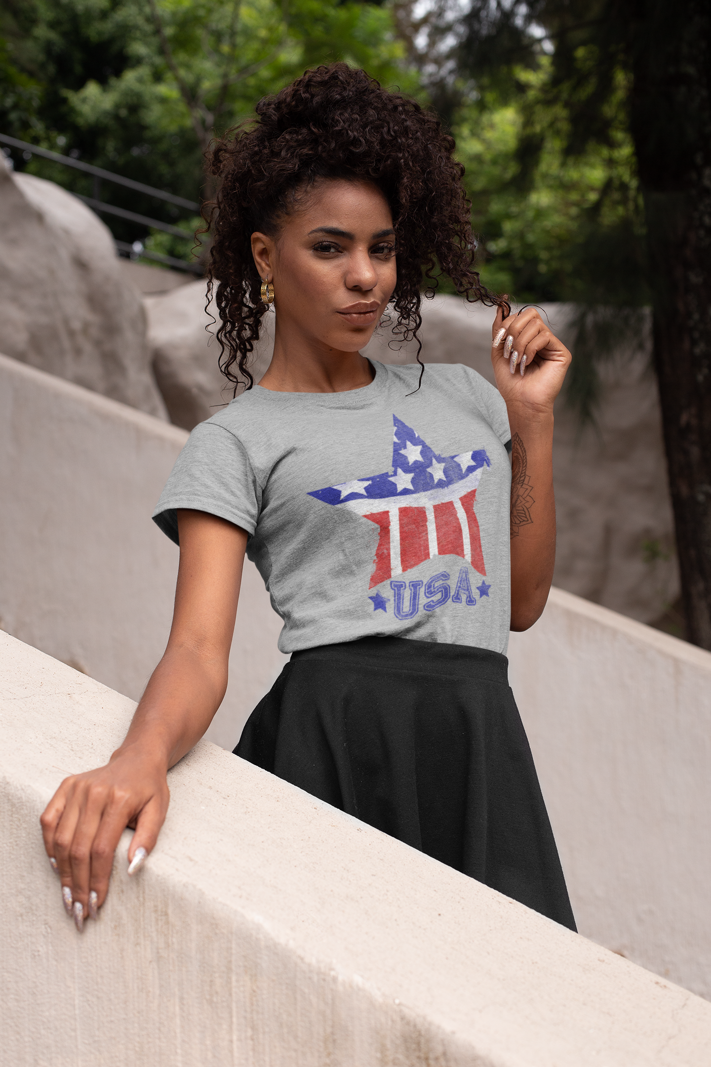 Woman wearing a gray t-shirt with a USA graphic design outdoors.