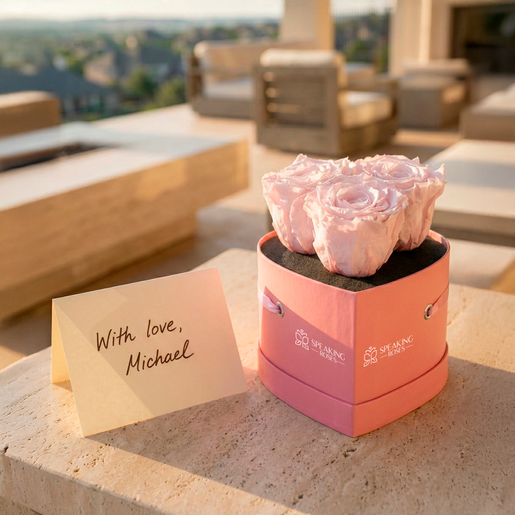 Pink roses in a decorative box with a card on a stone ledge outdoors