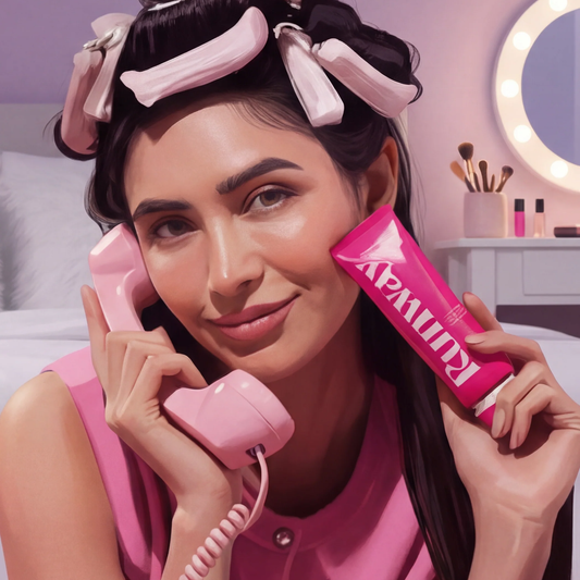 Runway cosmetic product in pink tube held by model with vintage pink hair rollers and retro telephone, beauty vanity setting with makeup brushes and illuminated mirror.