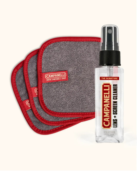 A Campanelli Lens + Screen Cleaner spray bottle next to three gray microfiber cloths with red borders, all on a light cream background.
