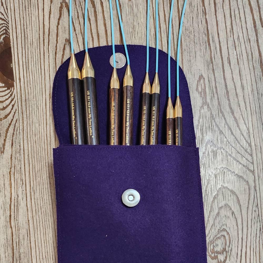 Set of knitting needles in a purple case on a wooden surface