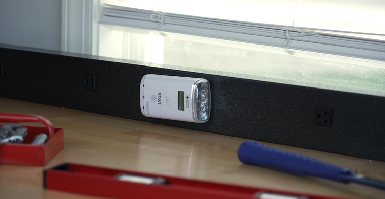 Digital multimeter on a wooden surface with tools in the foreground