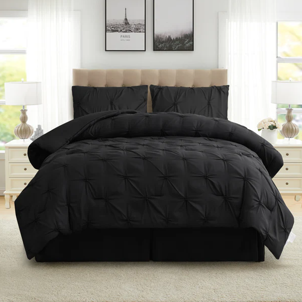Black quilted comforter set on a bed in a bright bedroom with large windows.