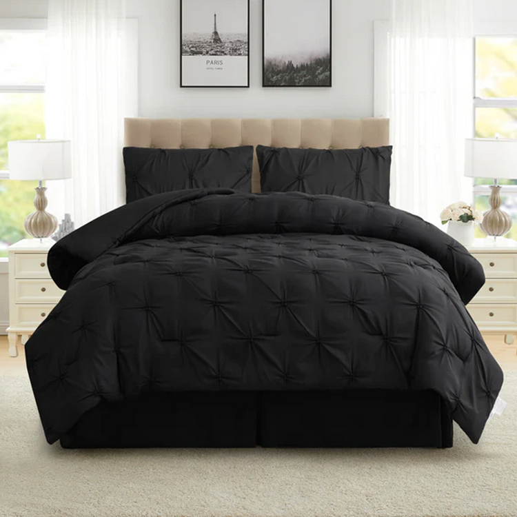 Black quilted comforter set on a bed in a bright bedroom with large windows.
