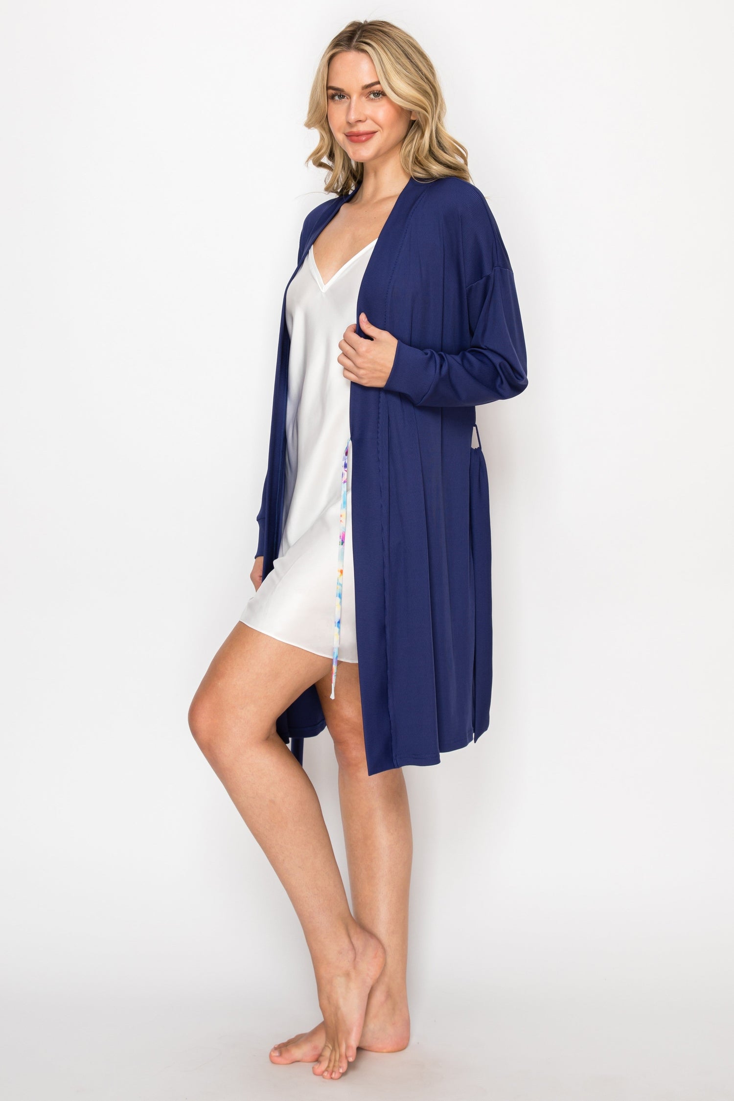 Woman wearing a navy blue robe over a white nightgown on a white background