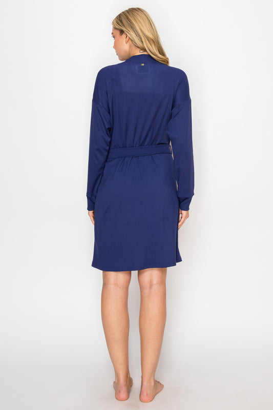 Woman wearing a navy blue robe over a white dress on a white background