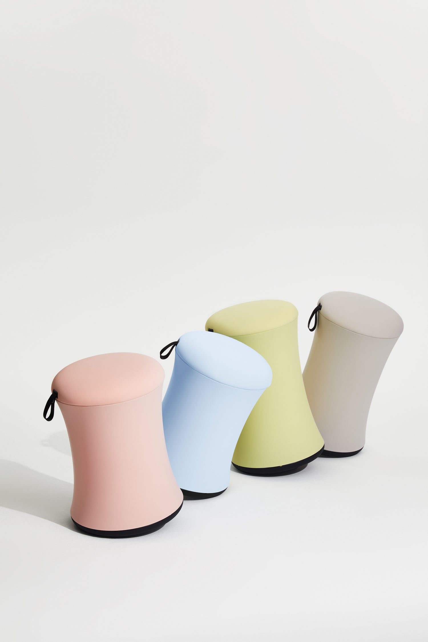 Four colorful stools in pink, blue, green, and gray on a white background
