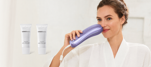 A woman in a white robe holds a purple handheld beauty device against her face, with two white cosmetic tubes labeled LINOMED Beauty floating on the left against a soft white background.