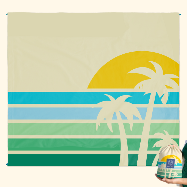 Beach towel with palm tree and sunset design held by a person