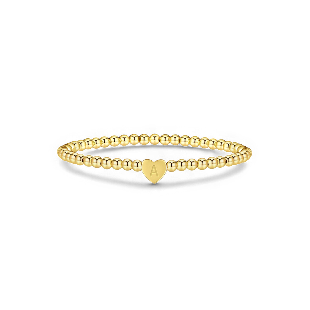 Gold ring with a heart-shaped charm on a white background