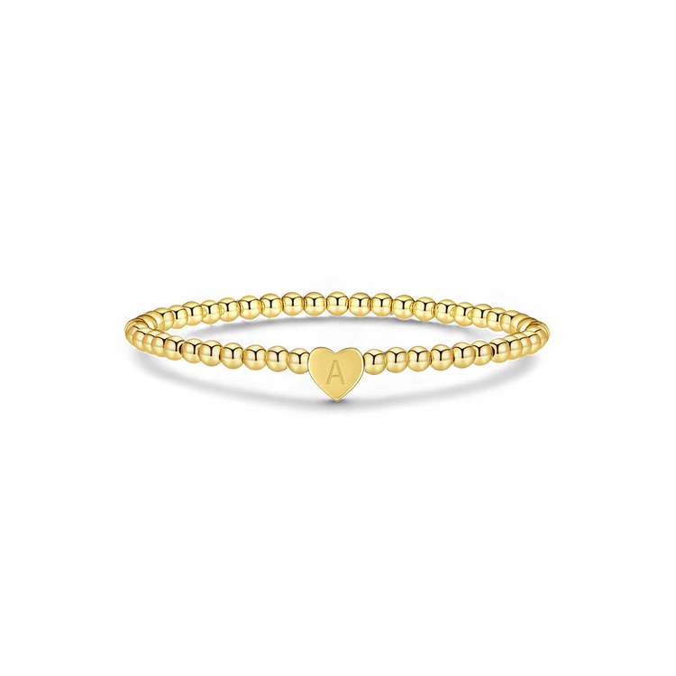 Gold ring with a heart-shaped charm on a white background