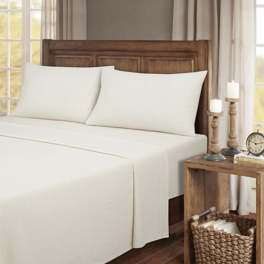 Neatly made bed with white bedding and wooden headboard in a bedroom setting.