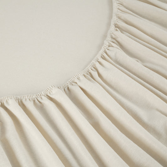 Neatly made bed with white bedding and wooden headboard in a bedroom setting.