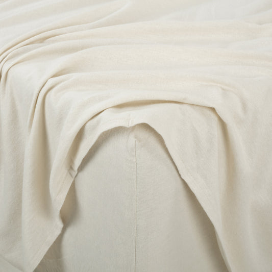 Neatly made bed with white bedding and wooden headboard in a bedroom setting.