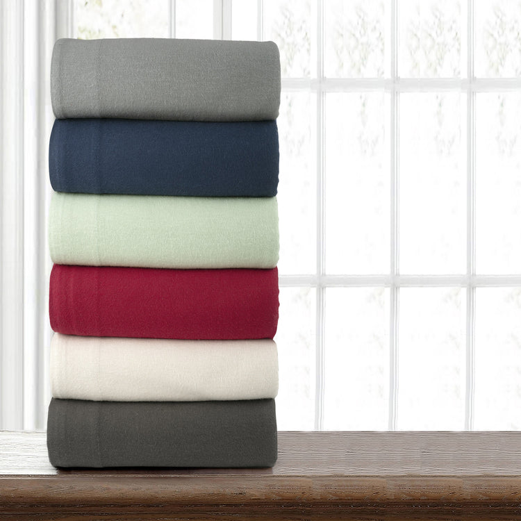 Stack of folded towels in various colors on a wooden surface with a window pane background
