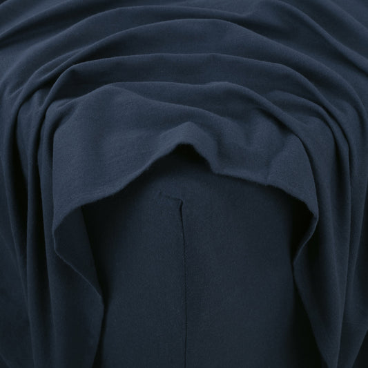 Navy blue bed sheets on a neatly made bed with wooden headboard and nightstand.
