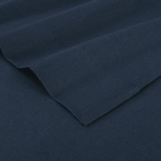 Navy blue bed sheets on a neatly made bed with wooden headboard and nightstand.