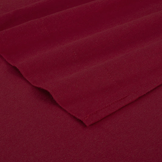 Red bed sheets on a wooden bed with a wooden nightstand and decor items.