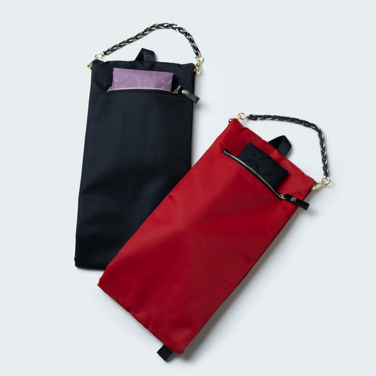 Red bag with black straps and chain detail on a light gray background