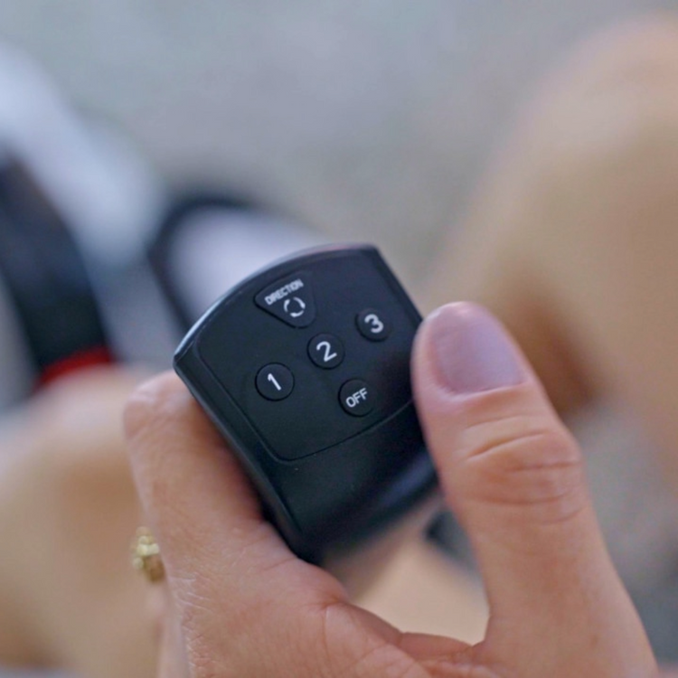 Hand holding a black remote control with buttons