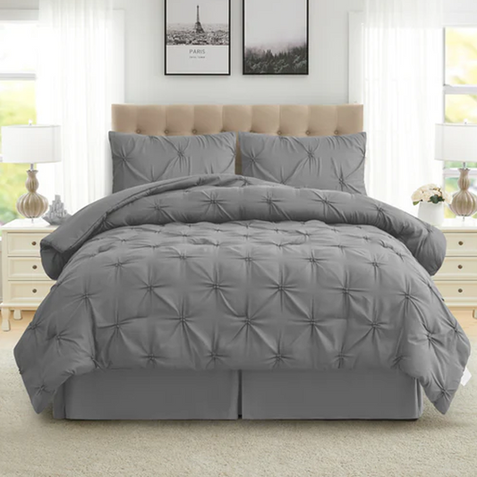 Gray comforter set on a bed in a bedroom with light-colored walls and furniture.