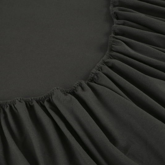 Dark gray bedding set on a bed with wooden headboard and nightstand in a bedroom setting.
