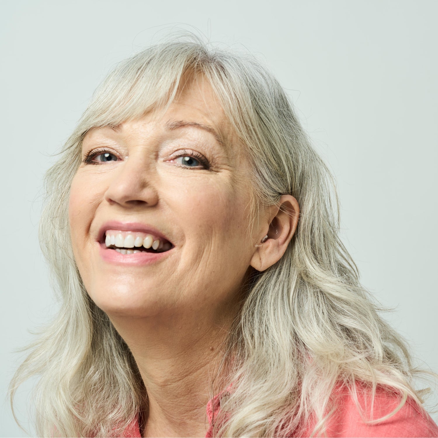Woman with gray hair smiling against a light background