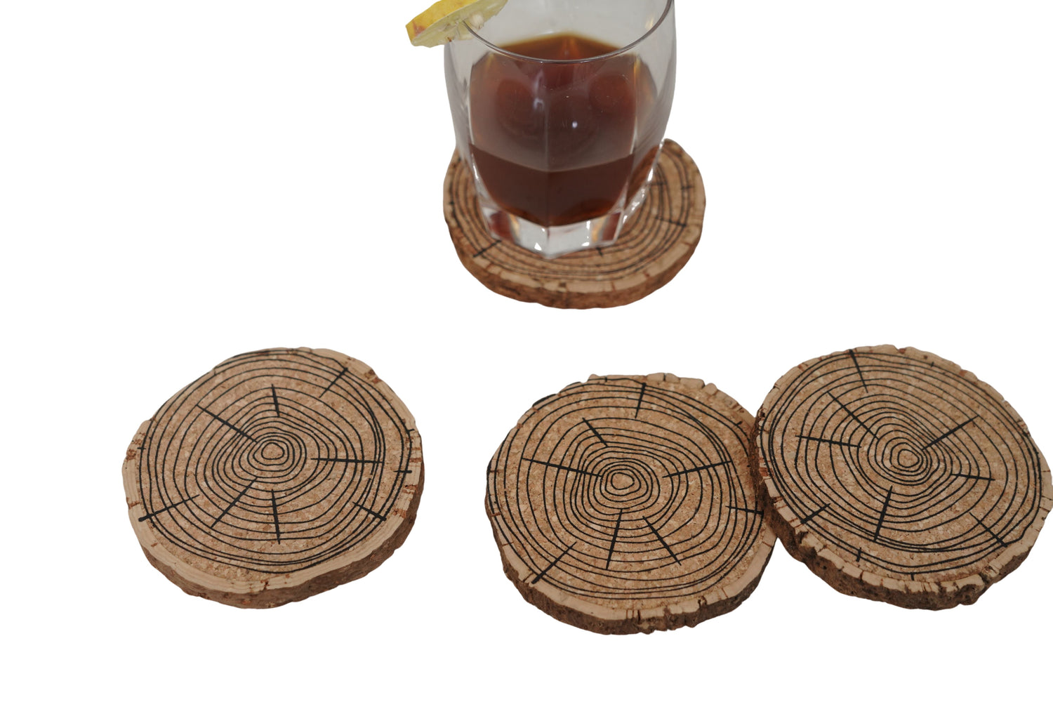 Set of three tree-ring patterned coasters with a glass of dark liquid on a white background