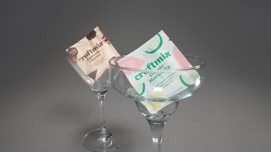Two cocktail packets labeled 'craftmix' on clear glass cocktail shakers against a gray background.