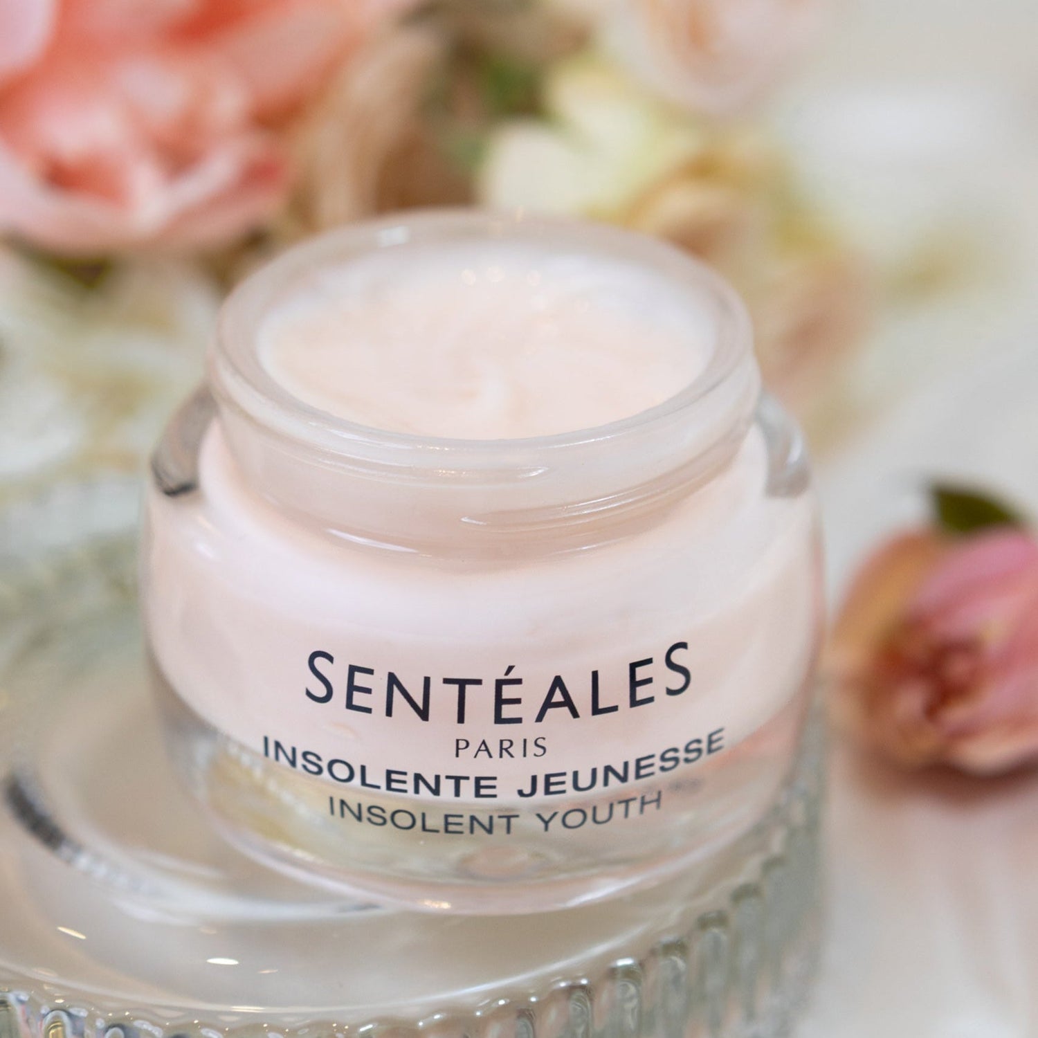 Skincare jar labeled 'Senteales' with flowers in the background