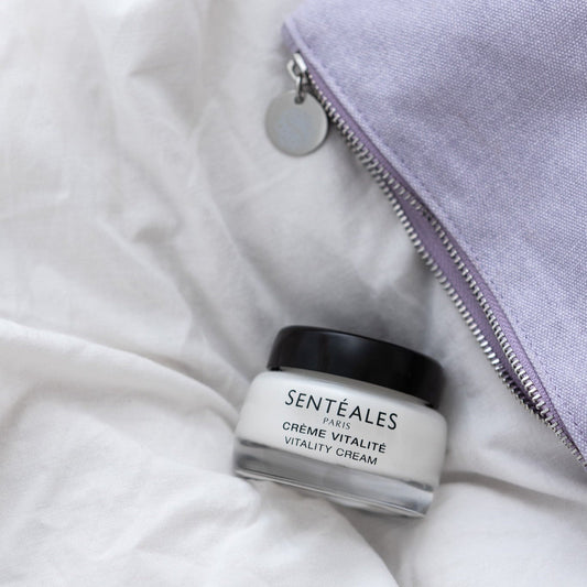 Jar of Senteaèles Paris Crème Vitalité on a woven mat with a pink flower in the background.