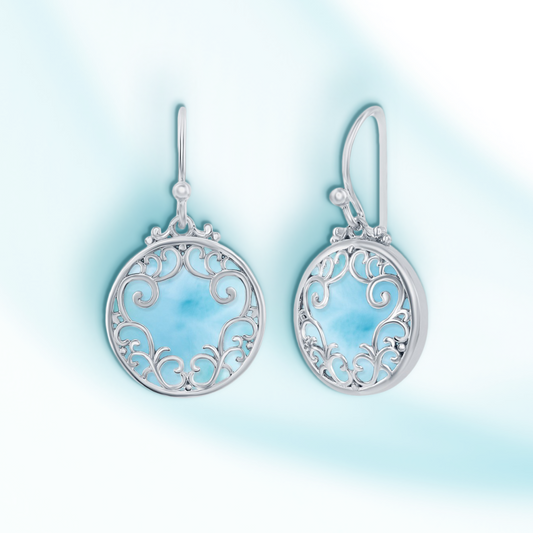 Silver earrings with intricate designs on a light blue gradient background