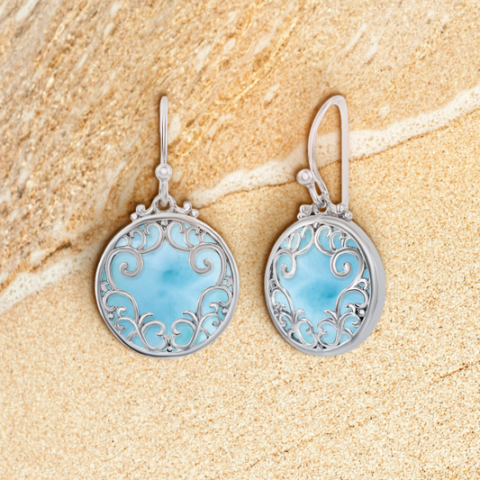 Silver earrings with intricate designs on a light blue gradient background