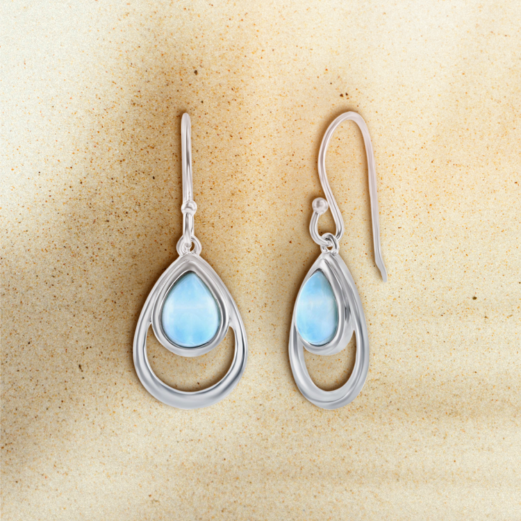 Silver teardrop earrings with blue gemstones on a beige background