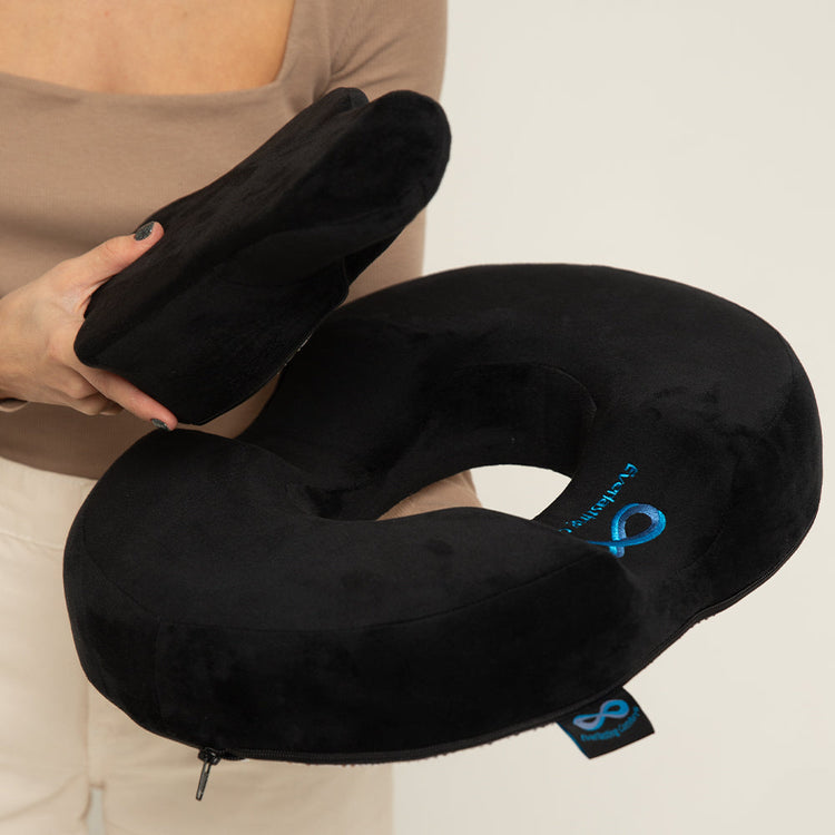 Black travel neck pillow held by a person against a neutral background