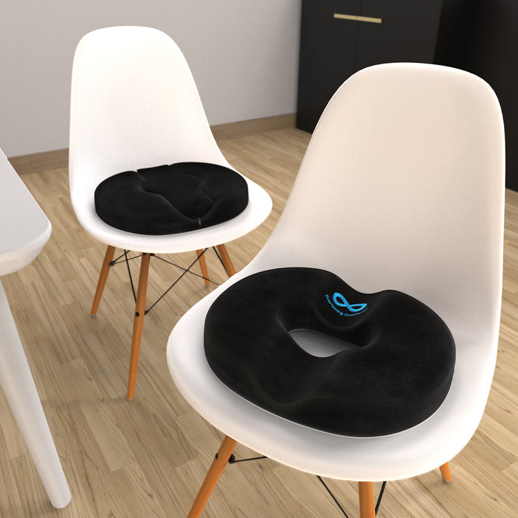 Black seat cushions on white chairs in a room with wooden flooring.